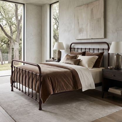 Heiressy 20th c Americana Iron Bed in Mocha Finish. A dark metal spindle-top bed frame with a curved headboard and footboard, styled with brown and beige bedding in a modern, neutral-toned bedroom.