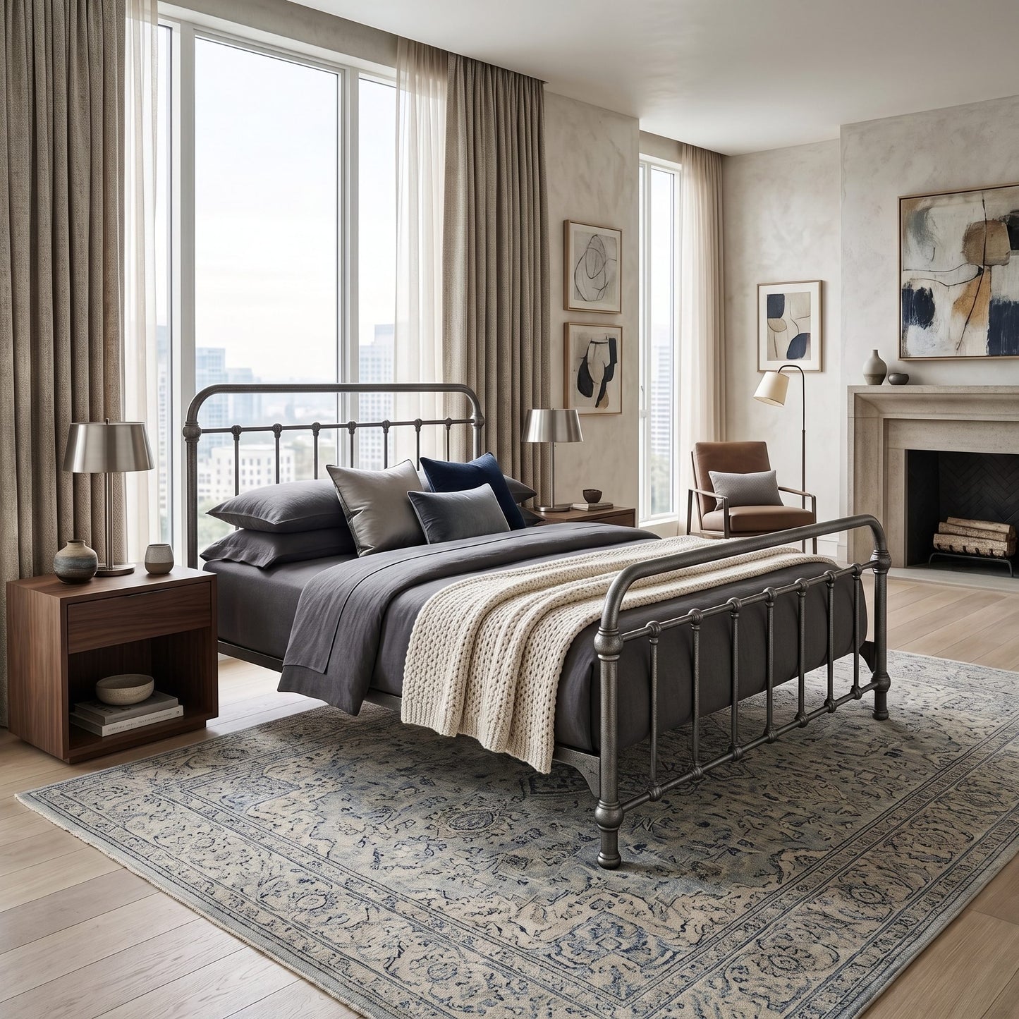 Heiressy 20th c Americana Iron Bed in Restored Silver Finish. A styled bedroom interior featuring a metal bed frame with gray bedding and a cream knit throw, placed on a large patterned rug in a modern, sunlit room with curtains, lamps, a chair, and a fireplace.