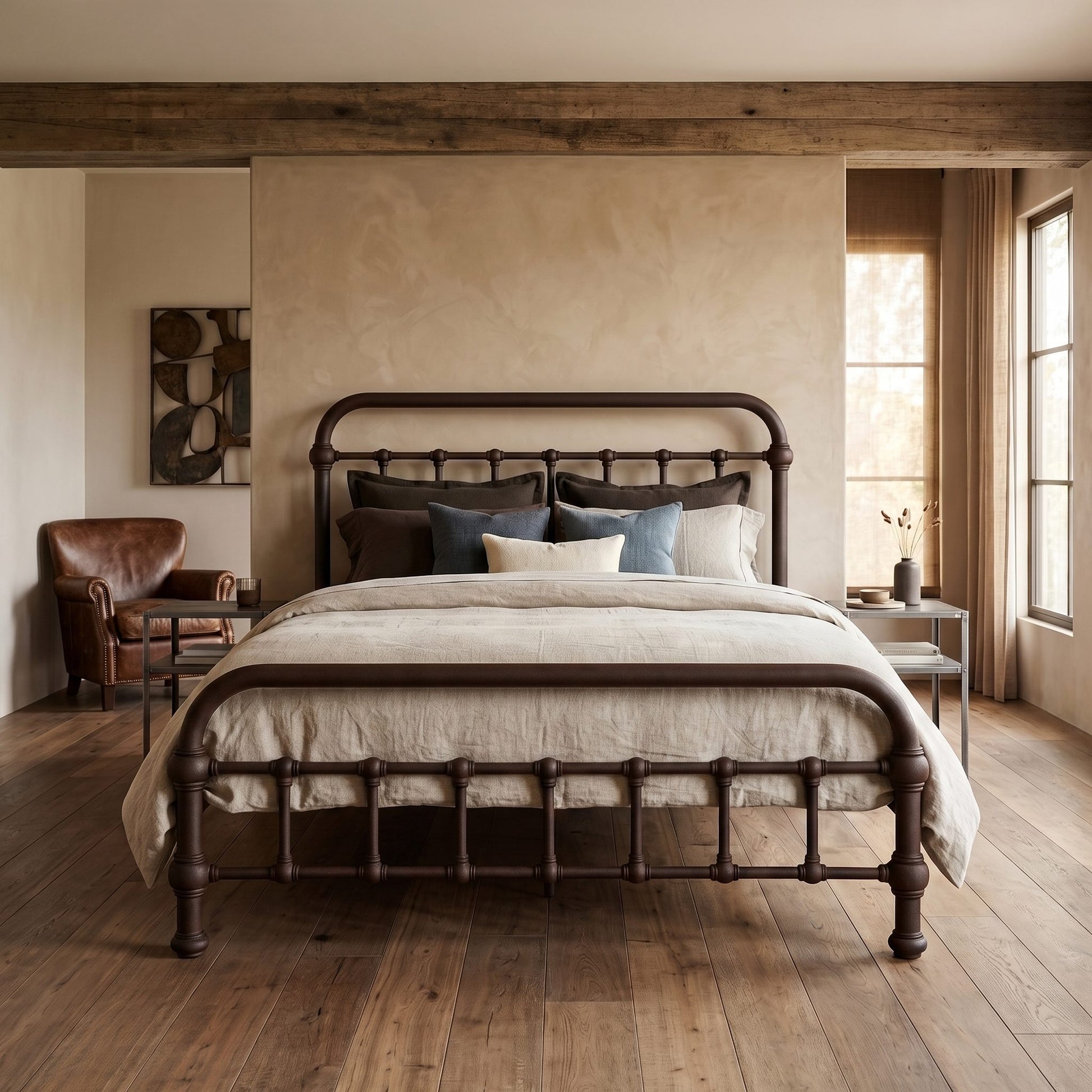 20th c Americana Low Profile Iron Platform Bed by Heiressy. A dark metal bed frame with a curved headboard and footboard, styled with neutral linens and blue accent pillows in a rustic, warm-toned bedroom.