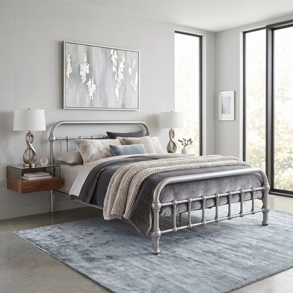 20th c Americana Low Profile Iron Platform Bed by Heiressy. A silver metal bed frame with a classic turned-post design, styled in a modern bedroom setting with gray and beige bedding, a blue-gray rug, and matching bedside tables and lamps.