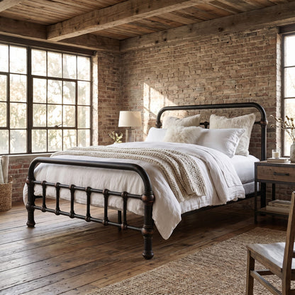20th c Americana Low Profile Iron Platform Bed by Heiressy. A dark metal bed frame with turned legs and a curved headboard and footboard, styled with white bedding and a textured beige throw in a rustic bedroom with brick walls and wood floors.